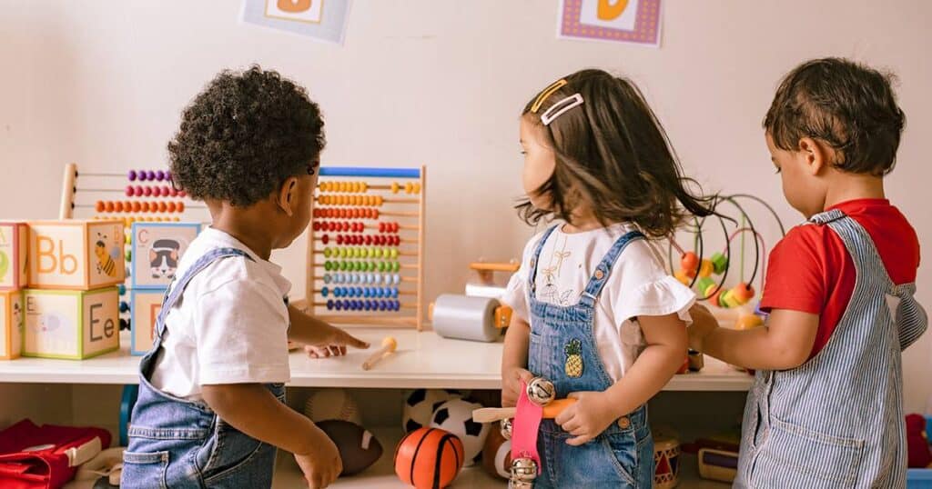 Three young children playing in classroom