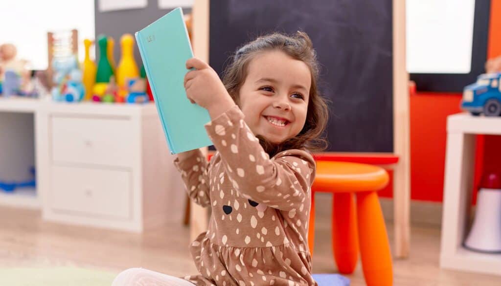 little child smiling while reading a book