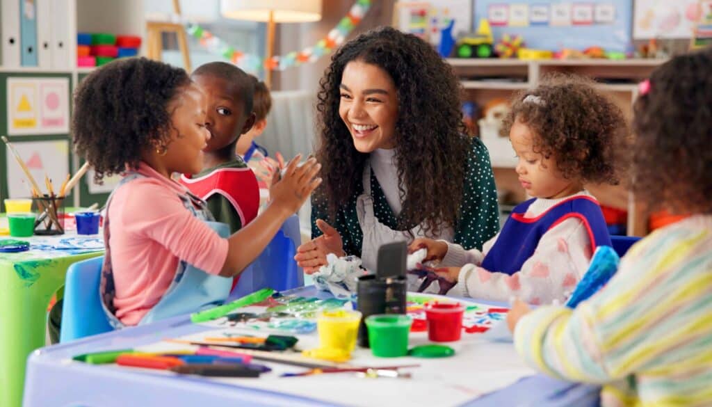 Happy preschool teacher helping doing handcraft activities with multilingual learners